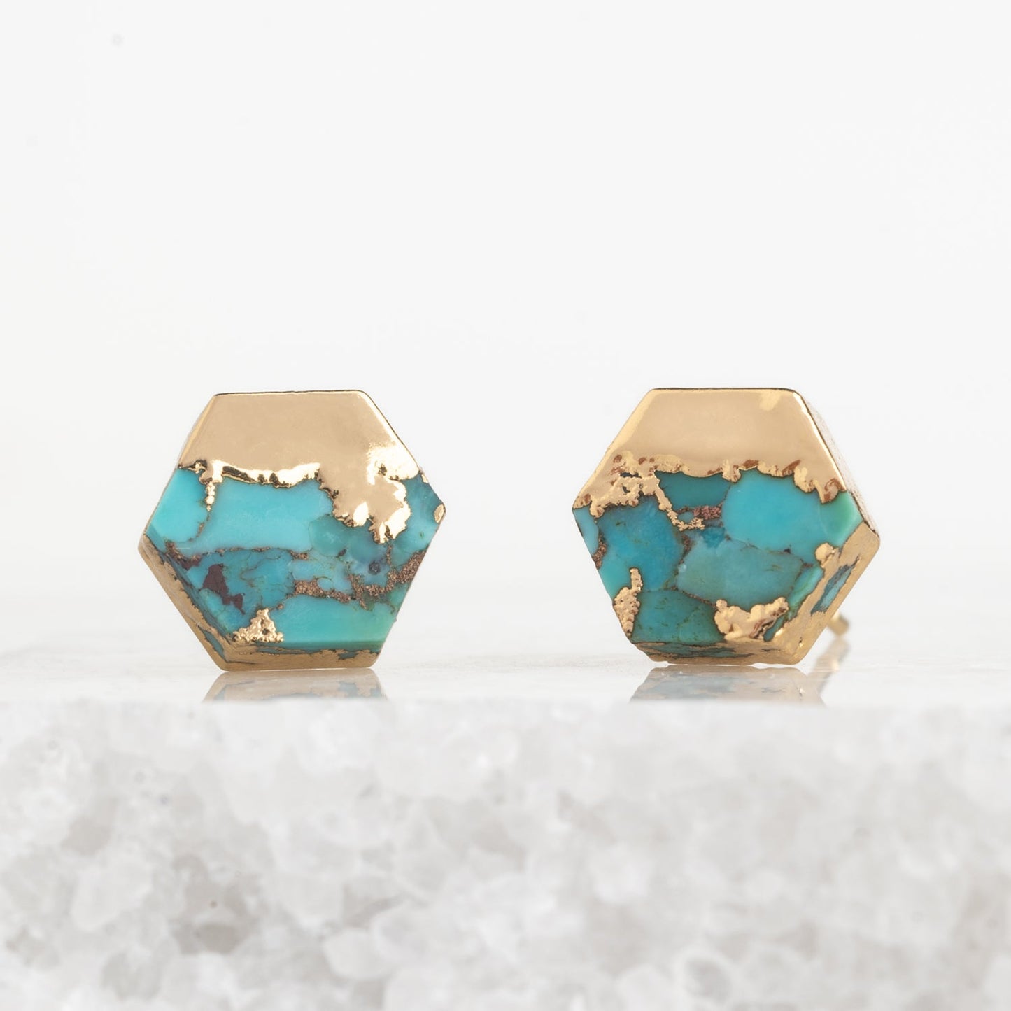 Hexagonal turquoise stones with gold accents on a white background