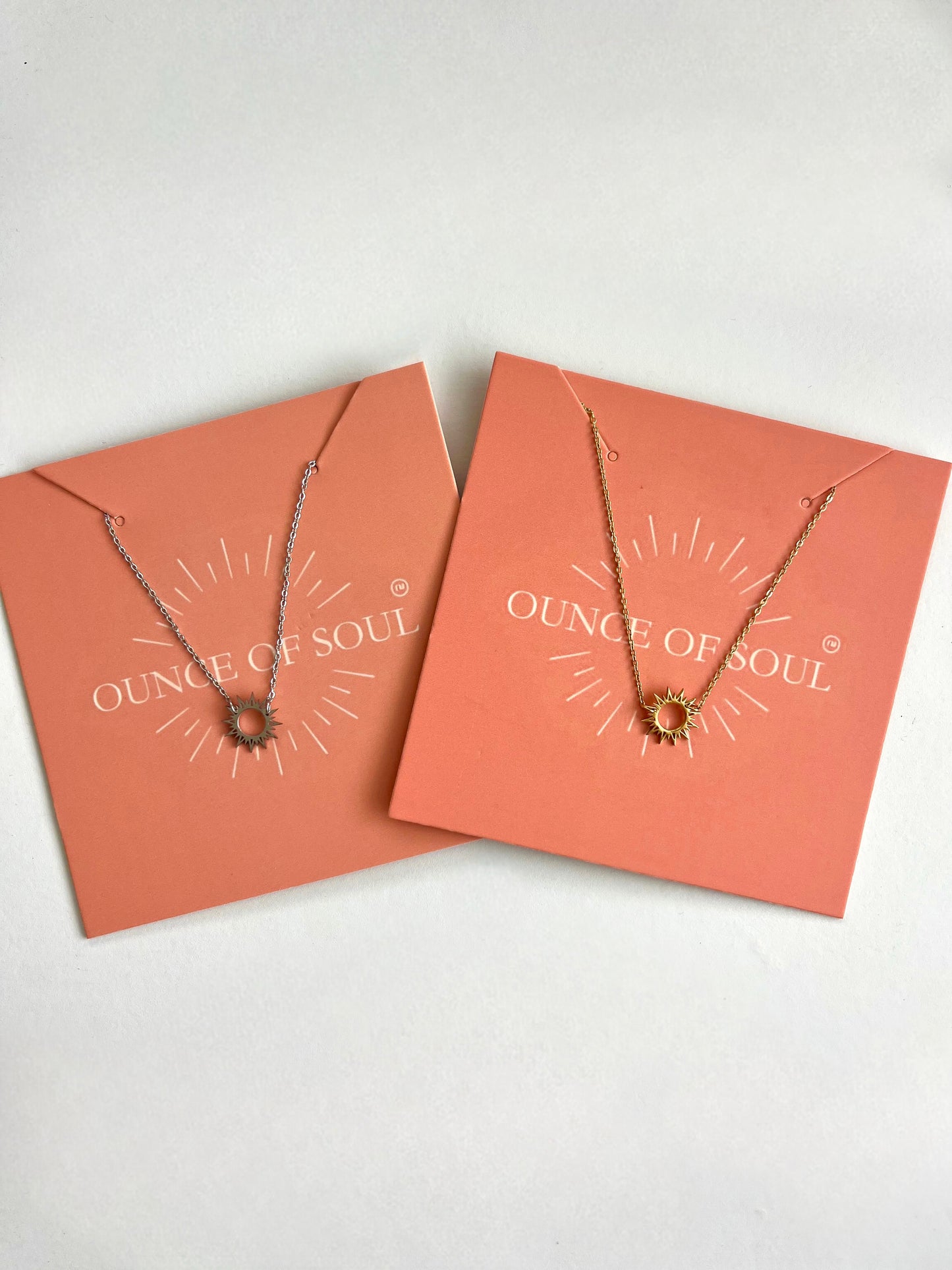 Two sun burst necklaces on 'Ounce of Soul' branded cards against a white background