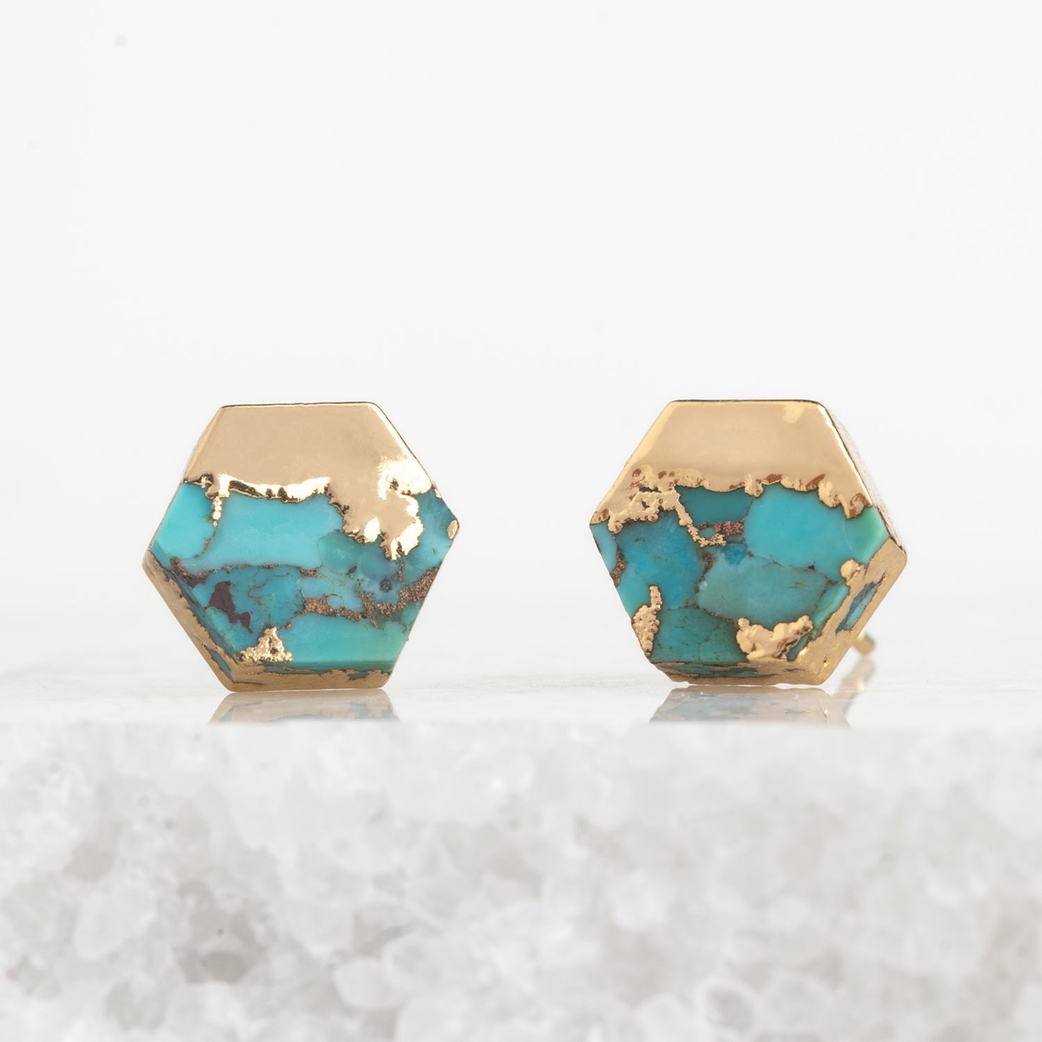 Hexagonal turquoise stones with gold accents on a white background
